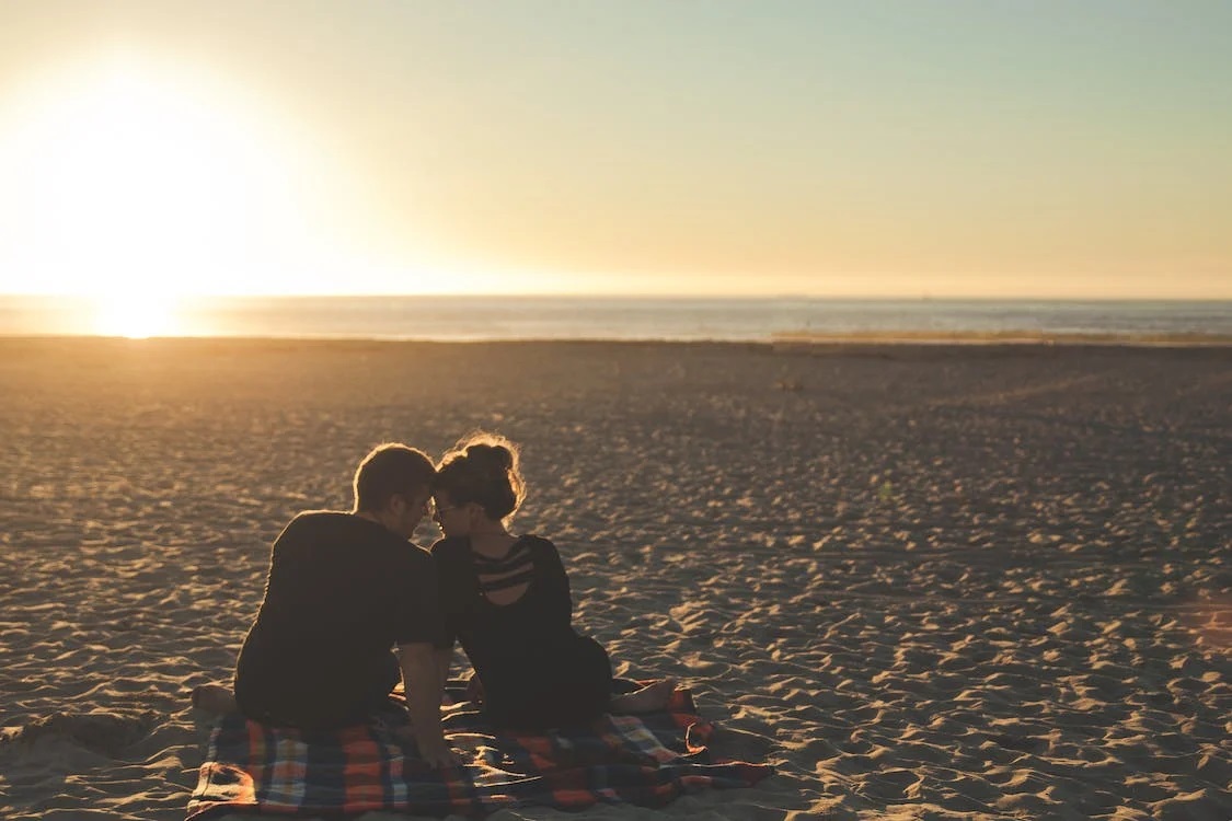 muž a žena na pláži při západu slunce 